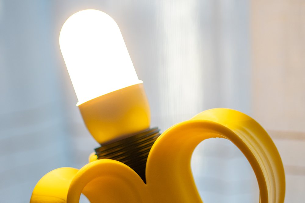 La lampadina accesa che esce dal cuore della banana, con le falde gialle della buccia aperte intorno